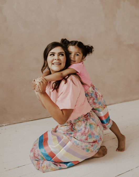 Taley with her daughter, wearing matching colorful outfits and smiling, showing the joy of being a mom and real estate agent.
